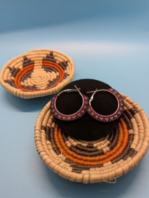 Adakair's Painted Earth hoop earrings with a Southwestern pattern of turquoise, deep red, and earthy brown beads, displayed on a black stand.