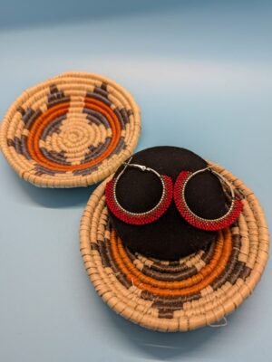 Adakair's Ristra Red brick stitch hoop earrings displayed on a black stand. The beads show a fiery gradient from bright crimson to deep red, mimicking a sun-dried chile ristra.