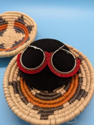 A detail shot of the Ristra Red hoop earrings, highlighting the meticulous brick stitch beadwork and the two-toned red glass beads on a stainless steel hoop.