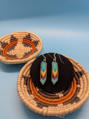 Hand-beaded feather earrings in Turquoise Sky with sterling silver hooks, turquoise base with yellow and red chevrons and soft silver edging
